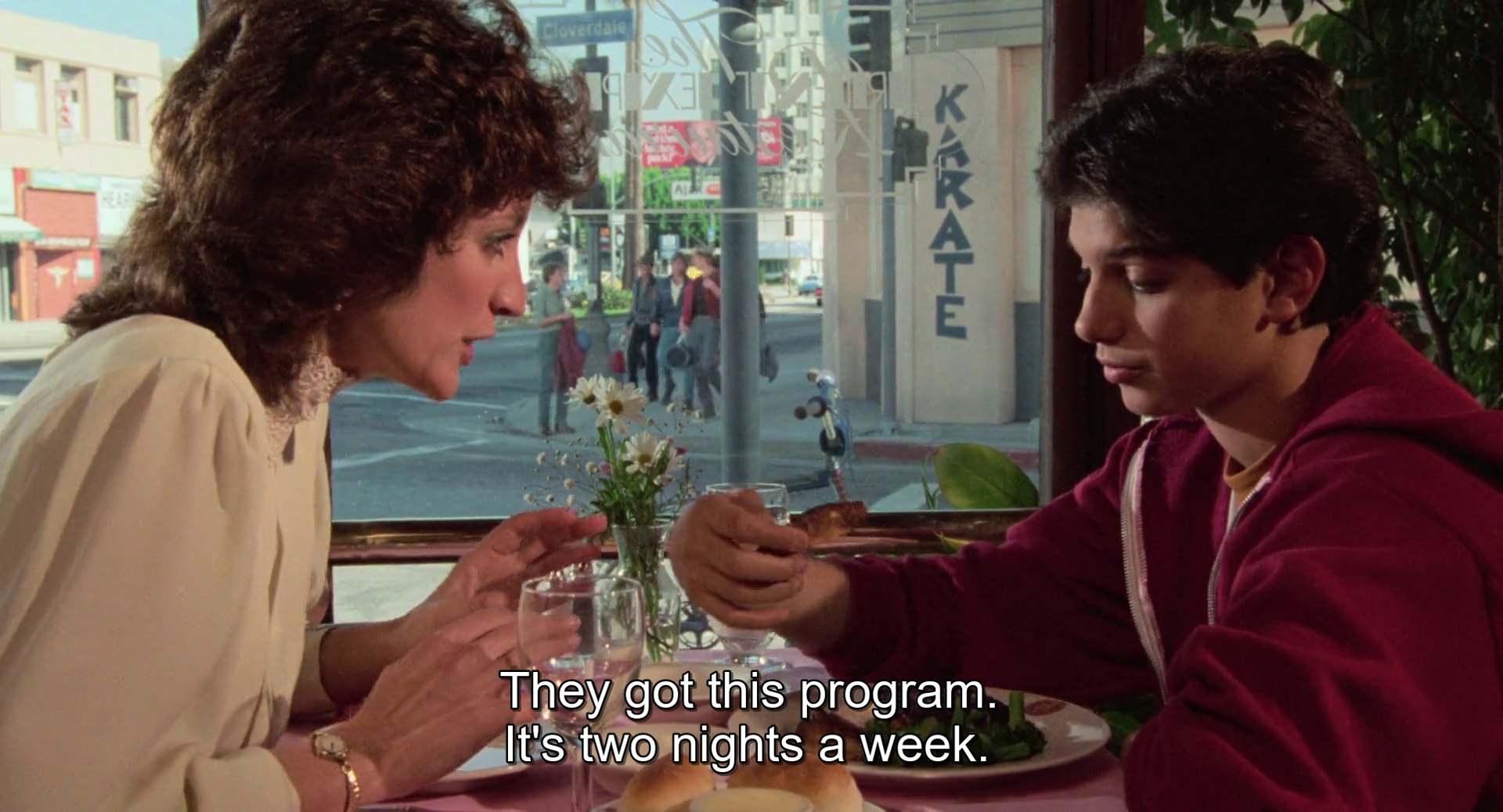 
Lucille and Daniel sitting in the restaurant, going through the dialogue written above.
The subtitles read: They got this program. It&rsquo;s two nights a week.
